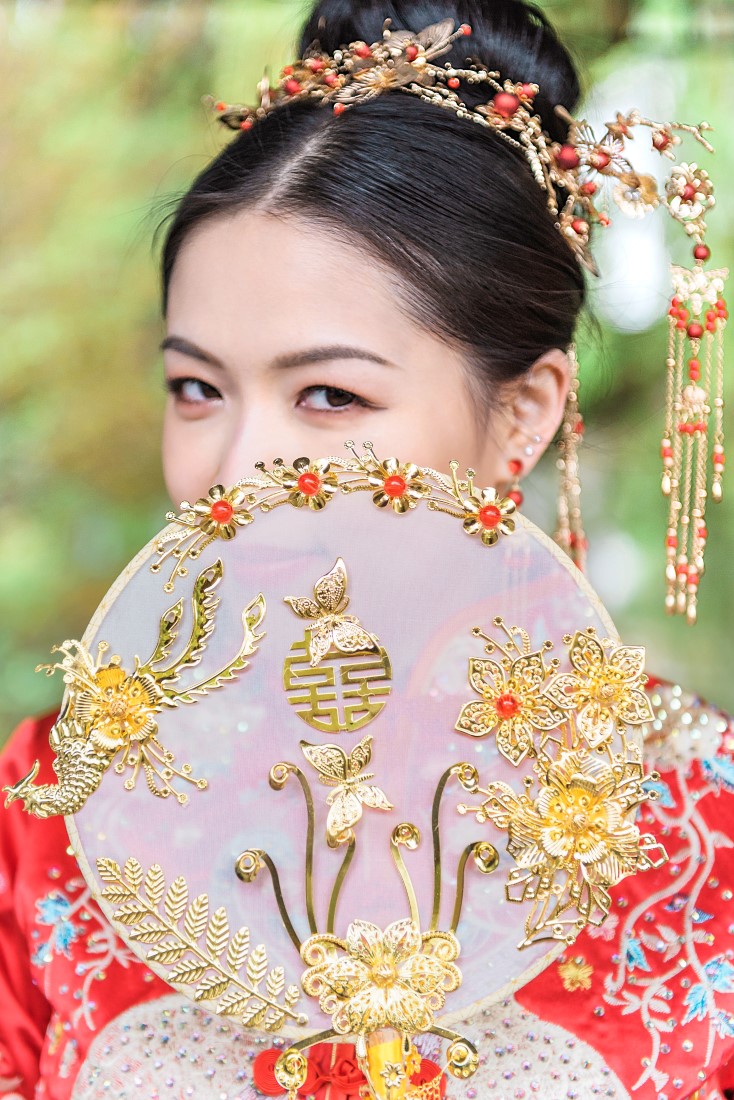 Chinese bride peeks over traditional fan