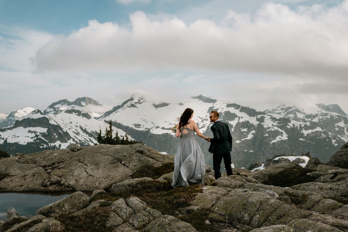 Newlyweds walk over mountaintop towards helicopter in BC