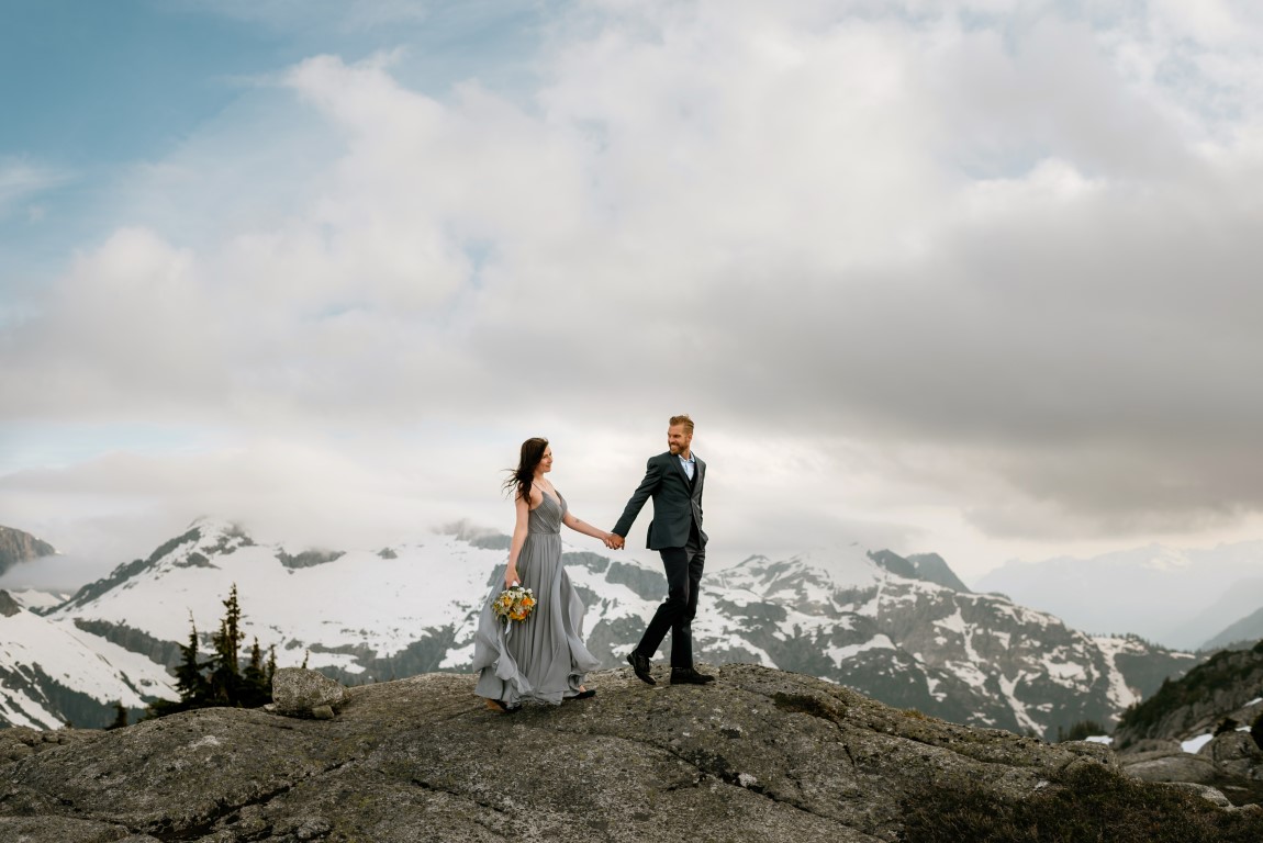 Groom takes brides hand on top of BC Mountain