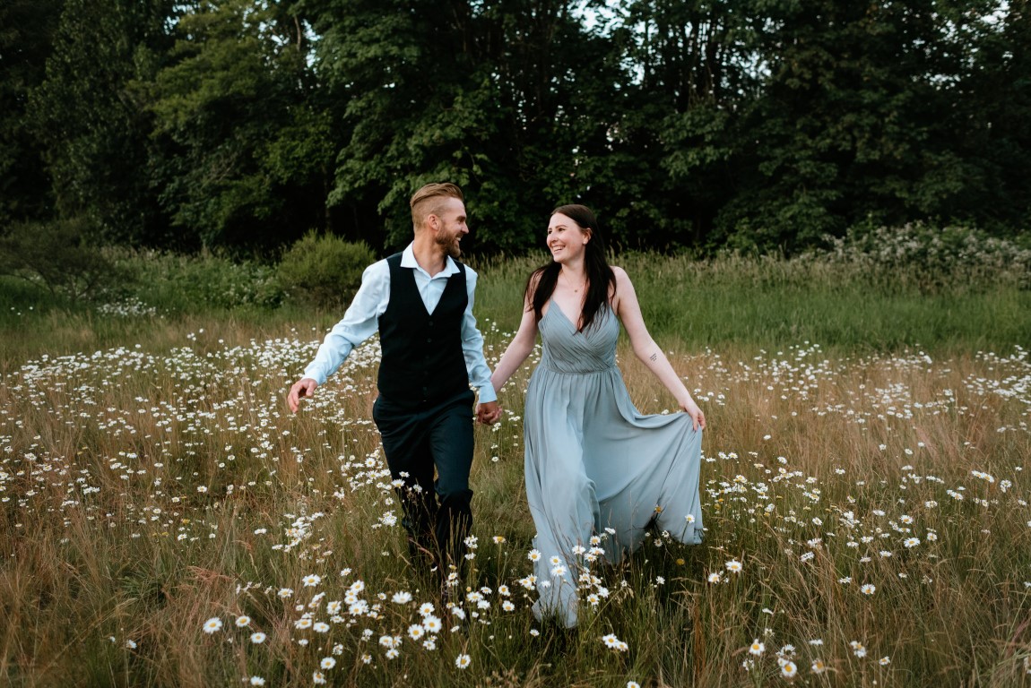 Newlyweds walk through mountain field of flowers by Leanne Sim