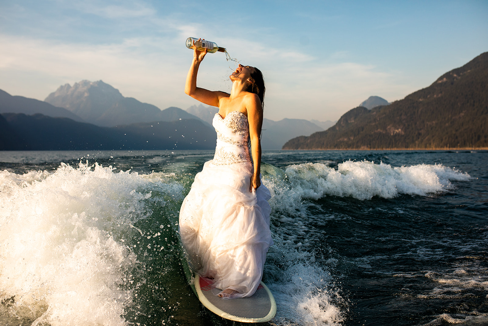 Surfer bride drinks champagne while surfing 