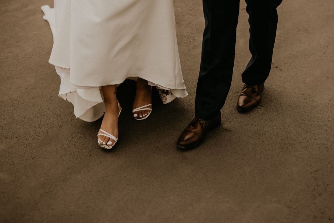 Ethereal Elopement newlyweds shoes as they walk along beach