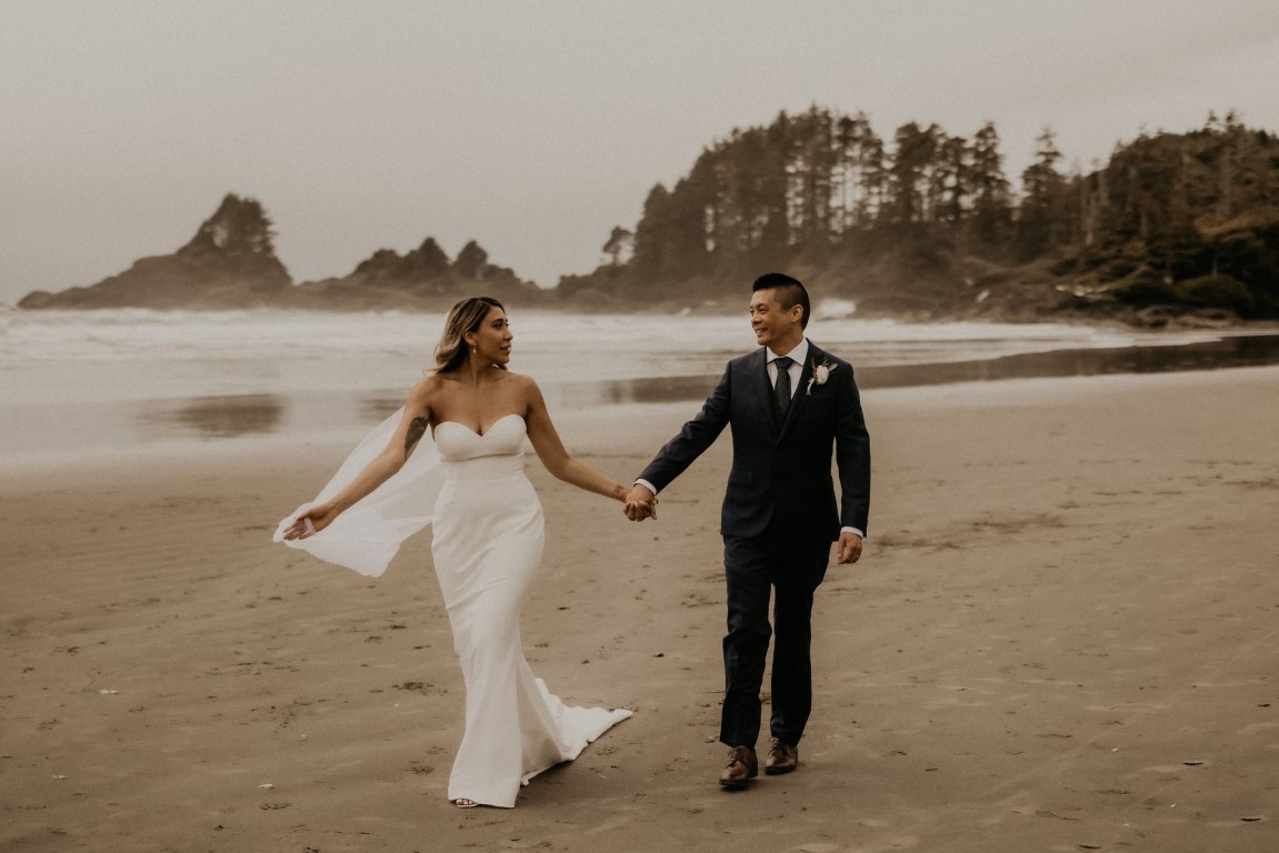 Ethereal Elopement Along Tofino Coastline newlyweds hold hands on the beach