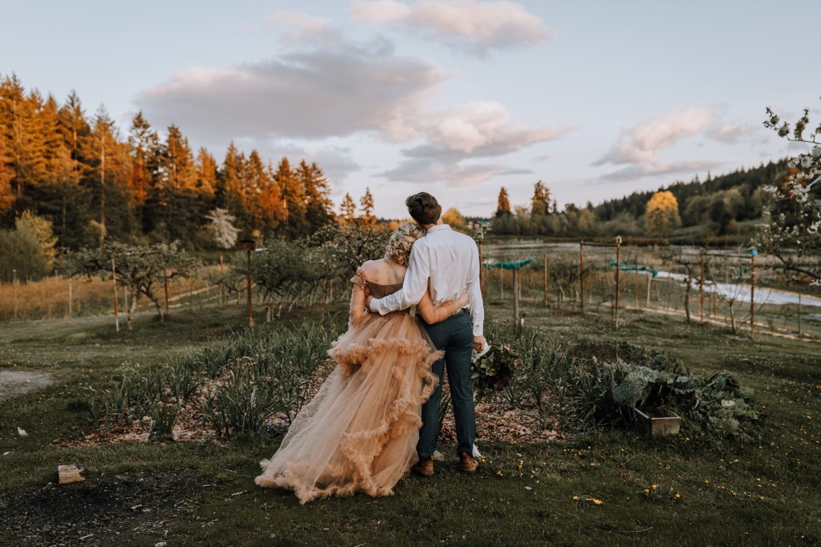 newlyweds look at fall forest colors while the sun sets on Vancouver Island