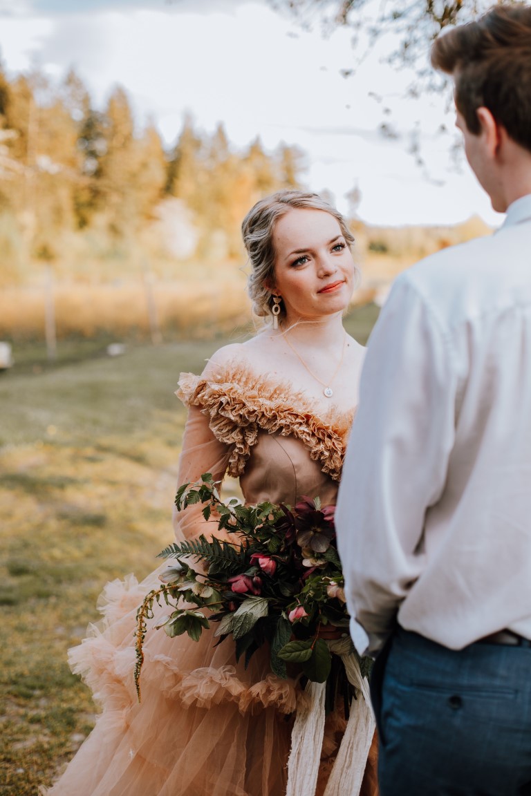 bride looks up to groom during farm ceremony