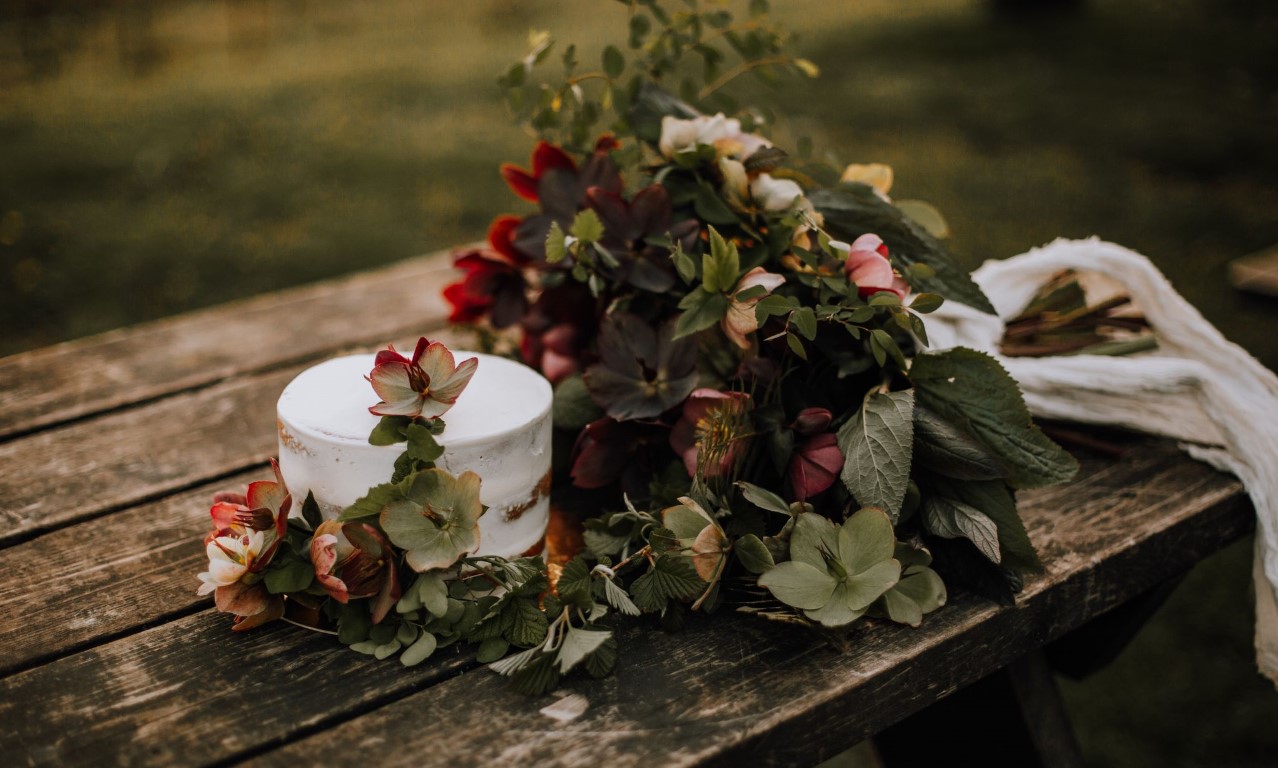 bridal bouquet and wedding cake on farm table decorated with hellebore flowers