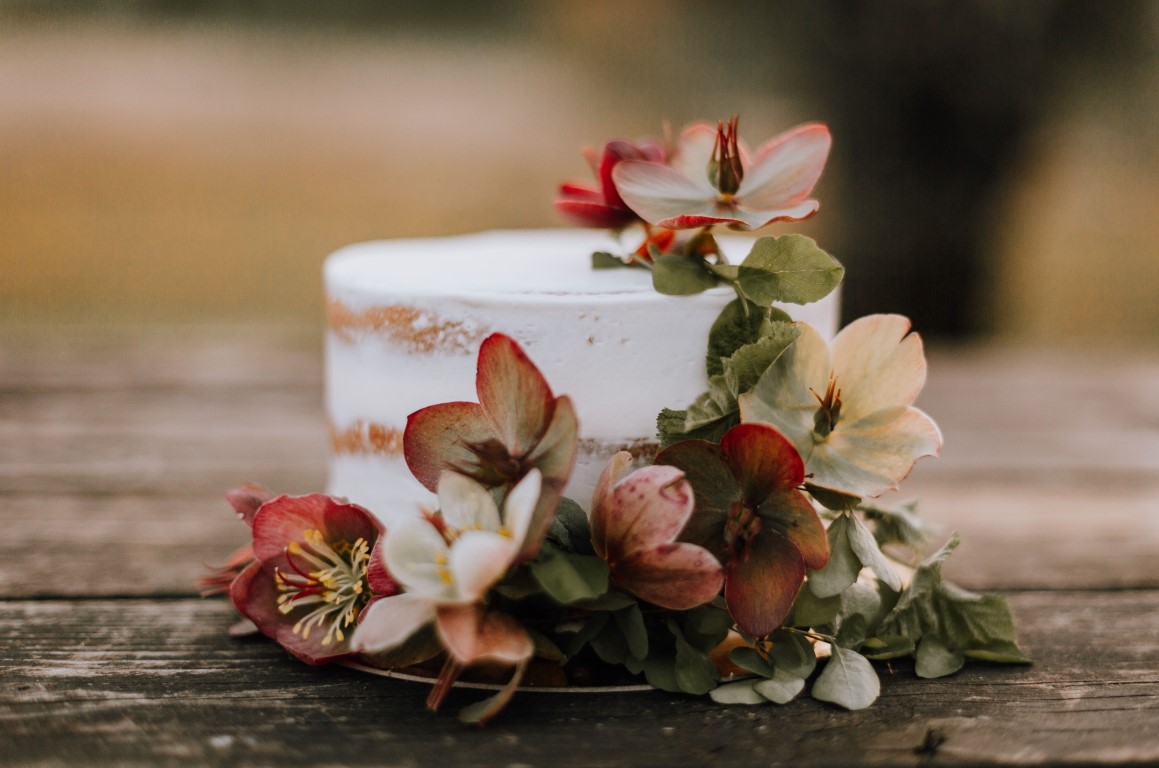 wedding cake covered in hellebore flowers on wood table