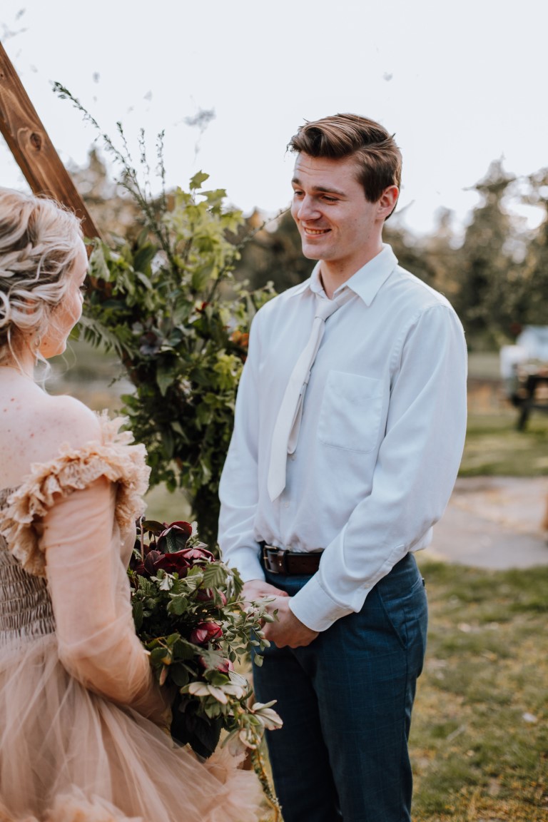 groom listens to brides vows at farm wedding