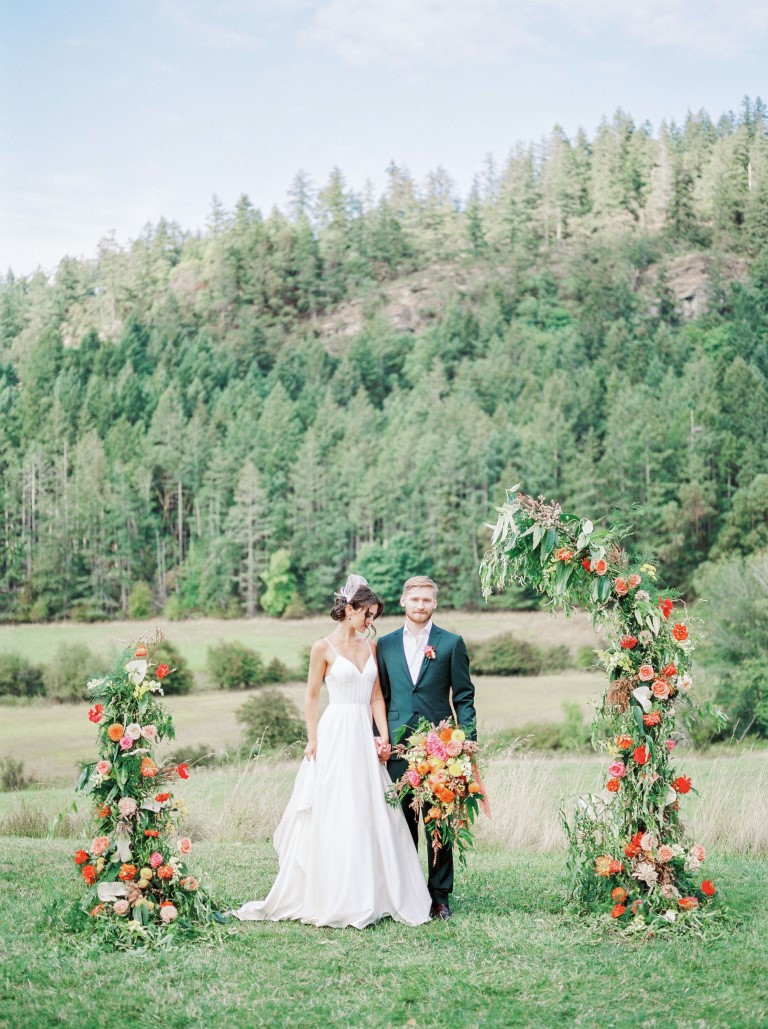Bird's Eye Farm wedding couple with floral backdrop in field ceremony