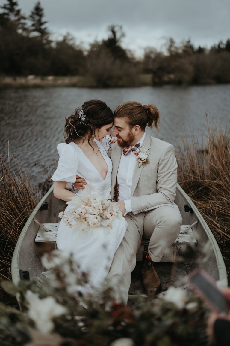 Bride and groom sit in a boat on Vancouver Island lake