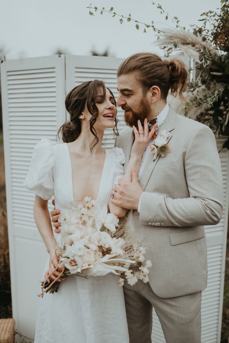 newlyweds with loving eyes and cream and white bridal bouquet