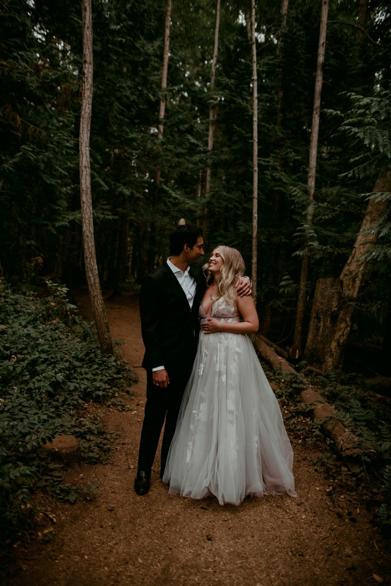 Newlyweds walk down a forest path on Vancouver Island