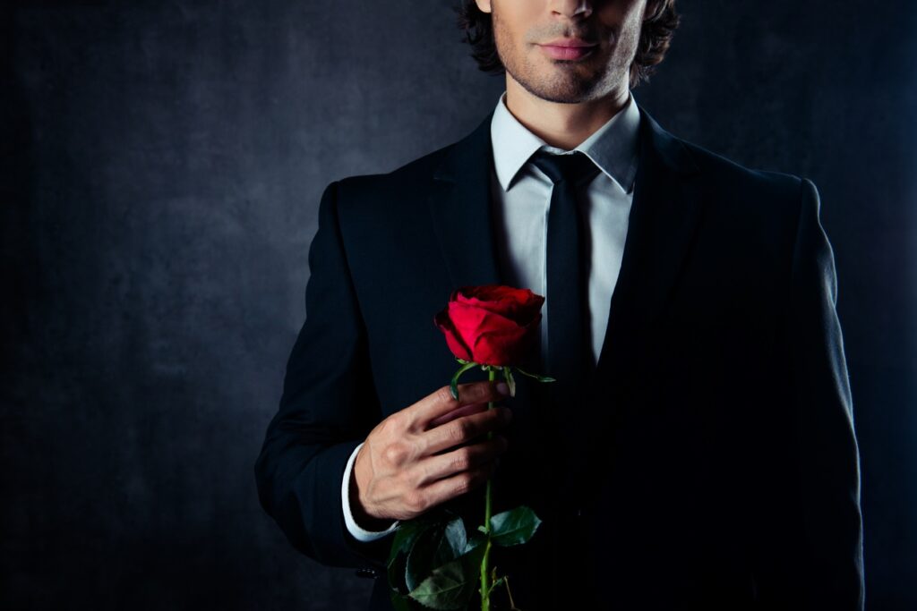 Man wearing Seville Tailors custom suit holds red rose