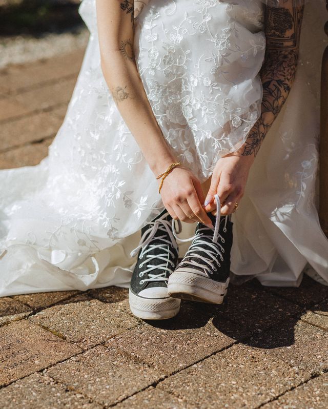 bride ties her black and white high-top running shoes