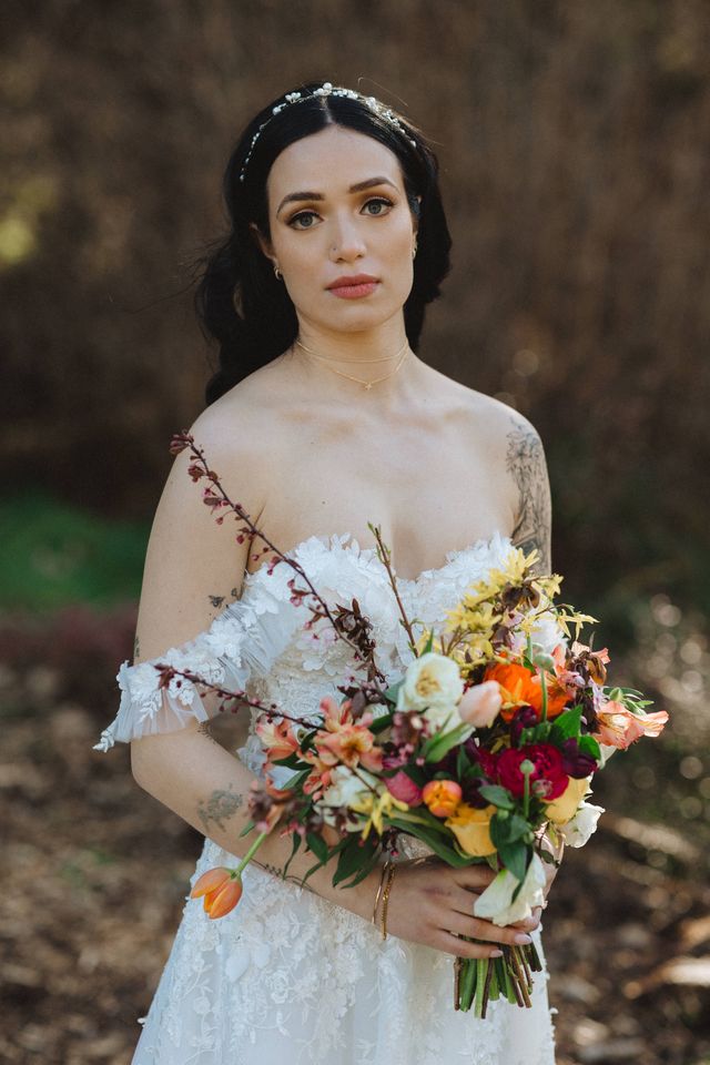 bride holds colorful bridal bouquet with orange tulips and wildflowers