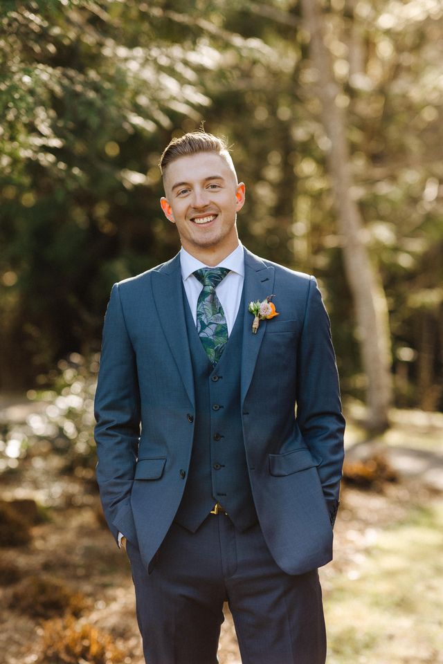 groom in his blue suit with orange rose boutonniere