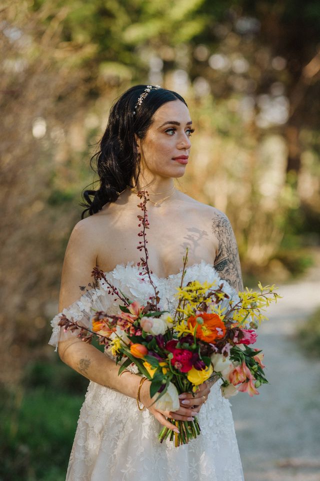 bride holding bouquet with yellow, coral, orange and pink wildflowers and tulips