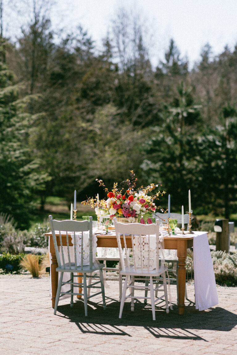 table with vibrant florals and glassware in botanical garden setting