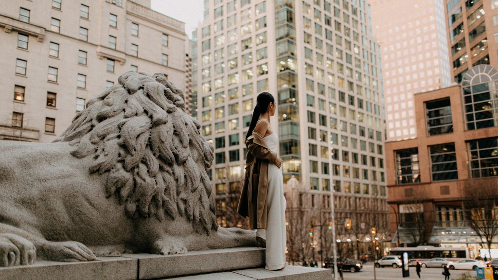 bride wearing jumpsuit with overcoat loosely draped down arms in downtown Vancouver amongst the high-rises.