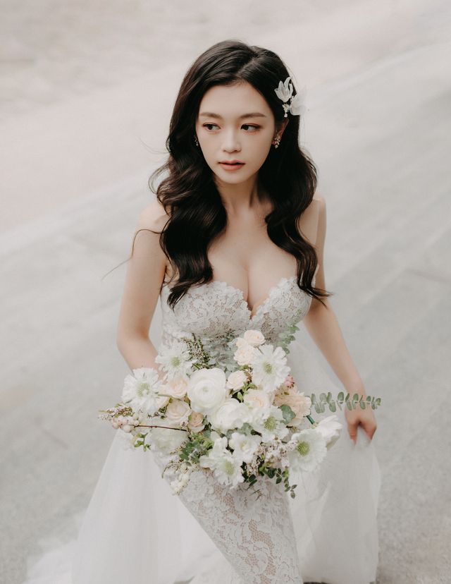 bride in lace gown holding white and peach florals bouquet with eucalyptus