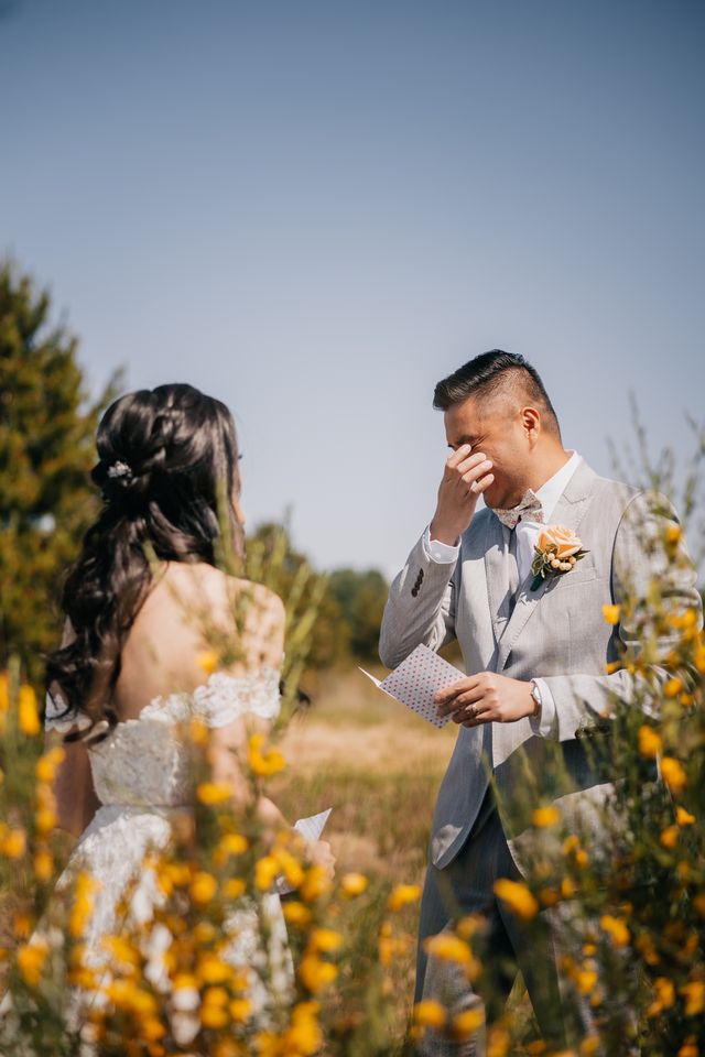 groom wipes away tears as he shares private moment with his bride as they exchange vows