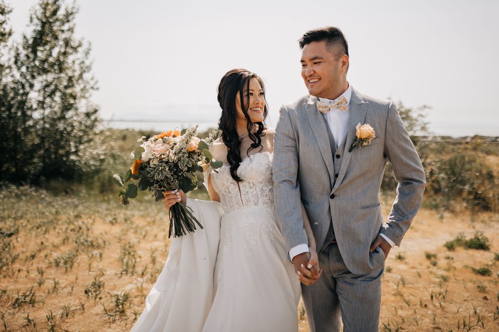 bride and groom stroll hand in hand all smiles