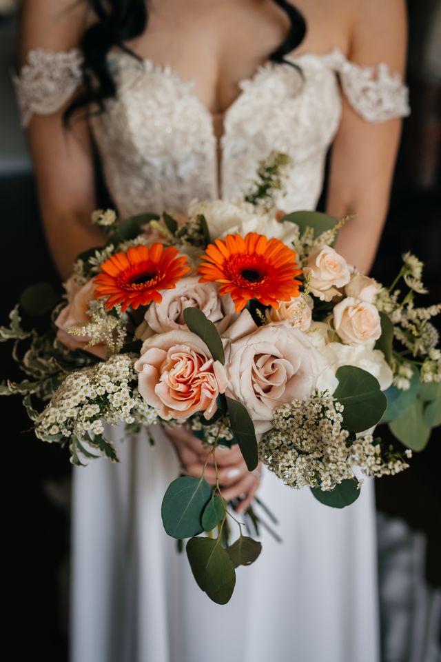 bridal bouquet of orange gerbera daisies , peach and neutral roses and greenery