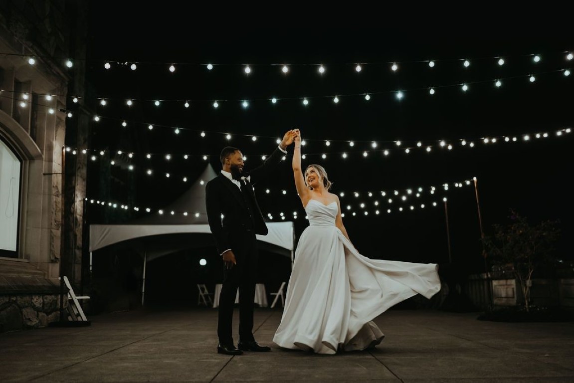 bride and groom dance under the Edison lights on the large outdoor deck