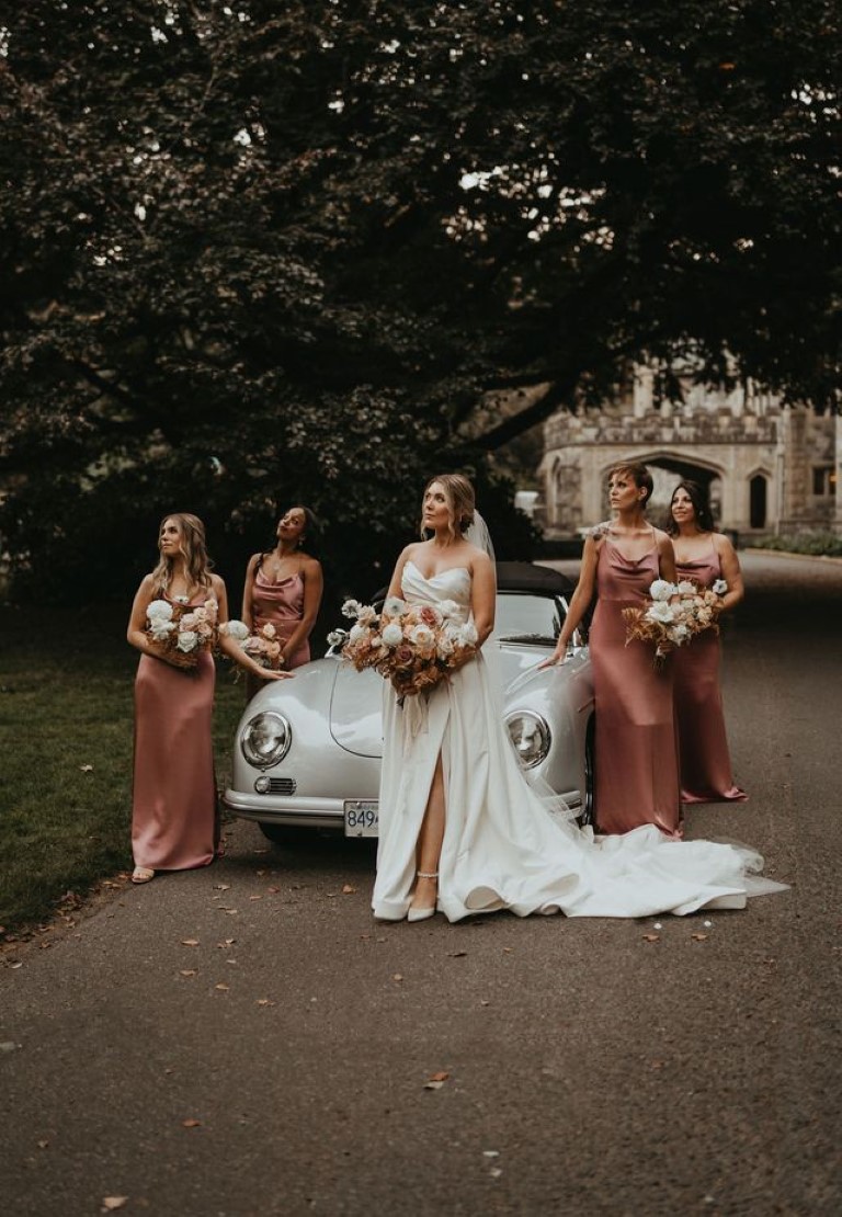 bride and her bridesmaids pose with vintage classic car