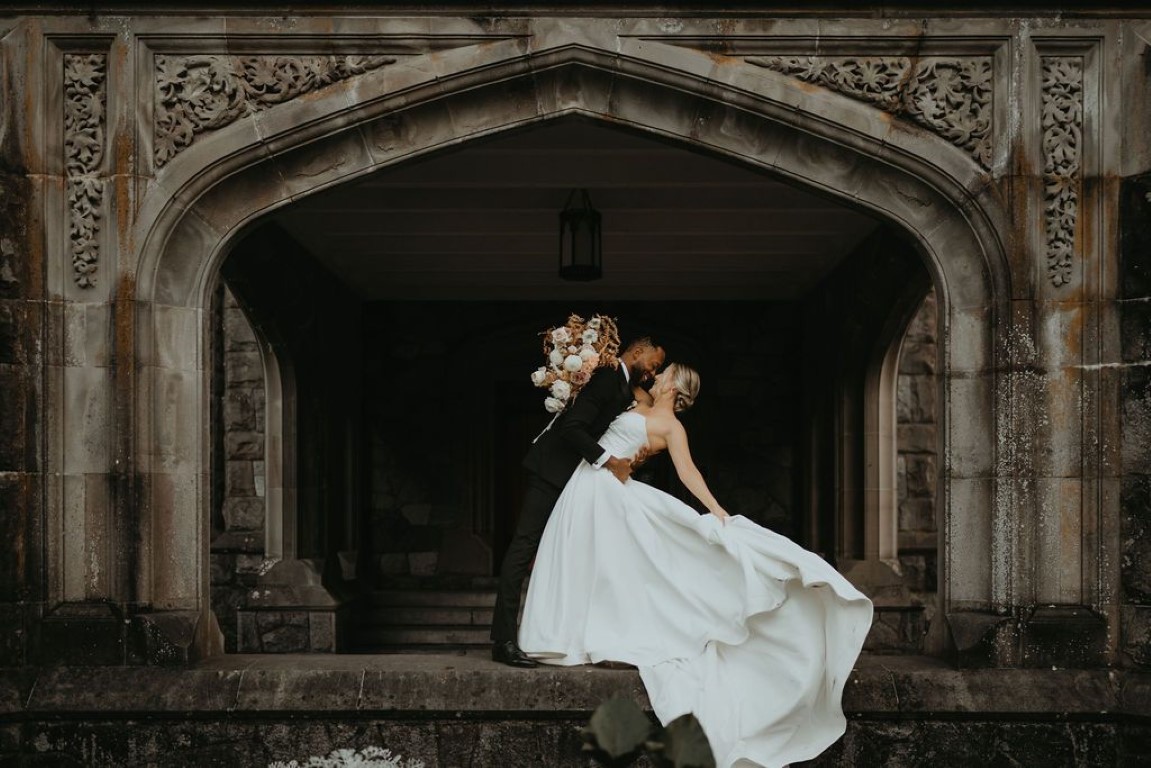 bride and groom in front of grand stone opening on veranda in castle garden