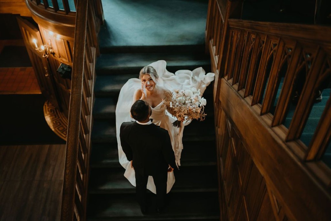 bride and groom stand together on the staircase in the castle foyer