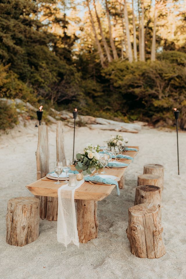 rustic wooden table and chairs on beach with lit torches