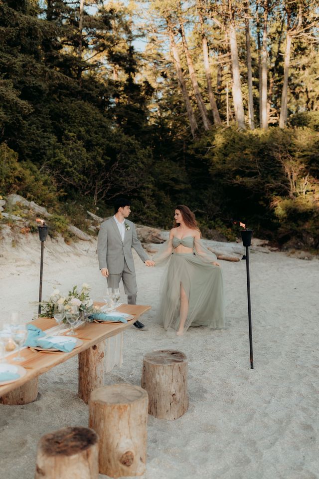 bride and groom with beach sweetheart table and lit torches