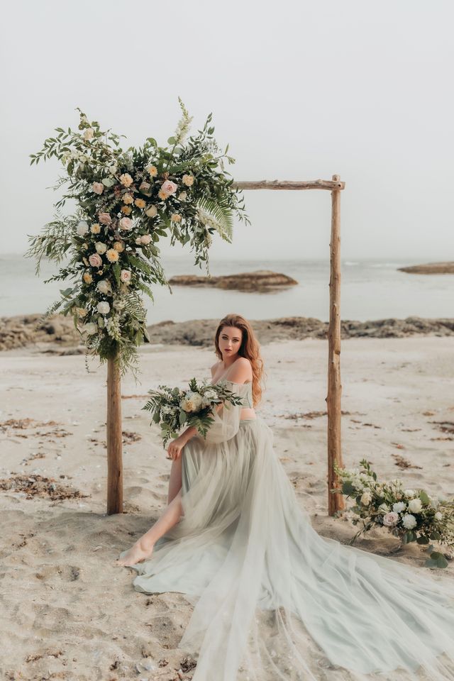 brie sits on stump inside arch on beach