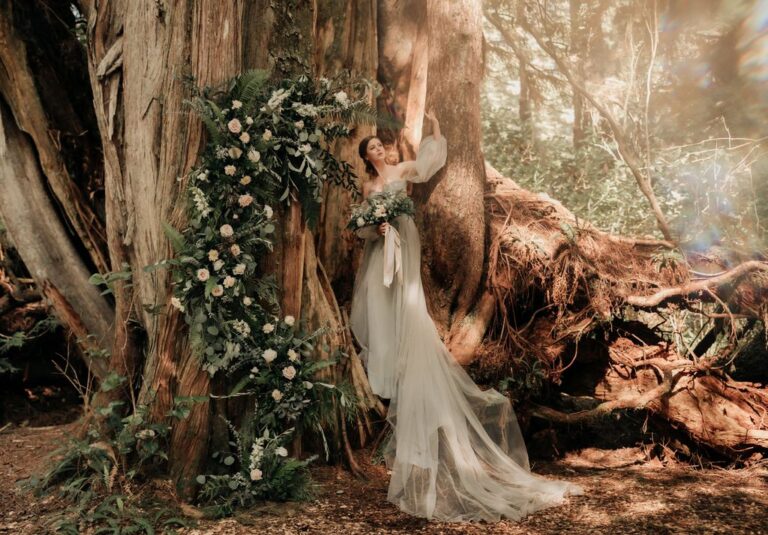 bride poses arm upward at huge tree base