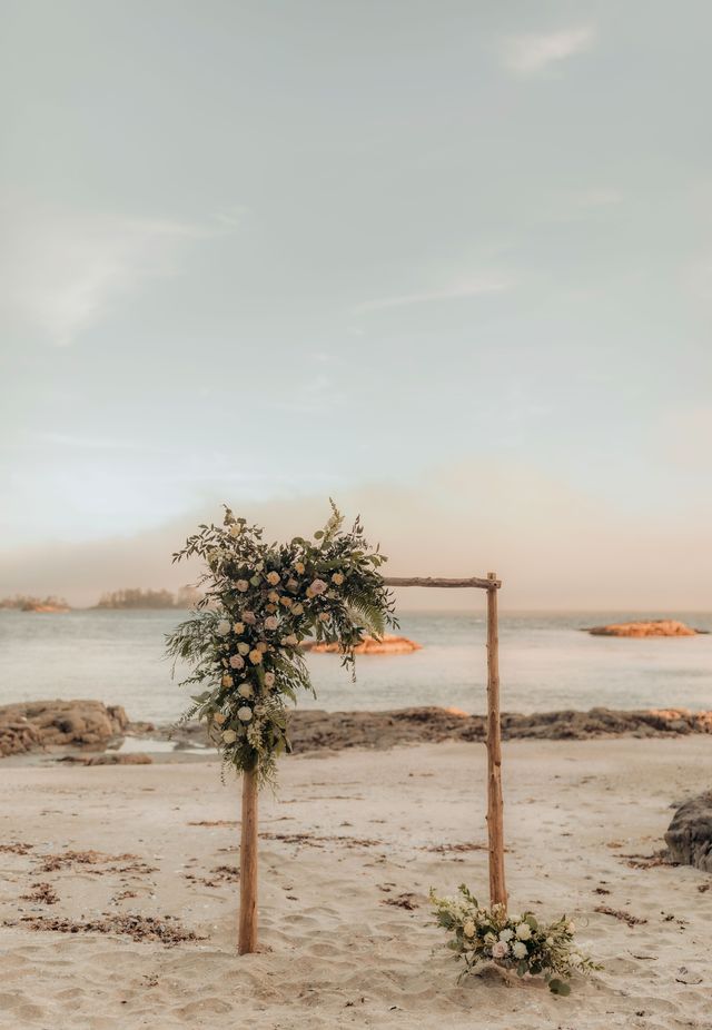 floral arch on beach at sunset