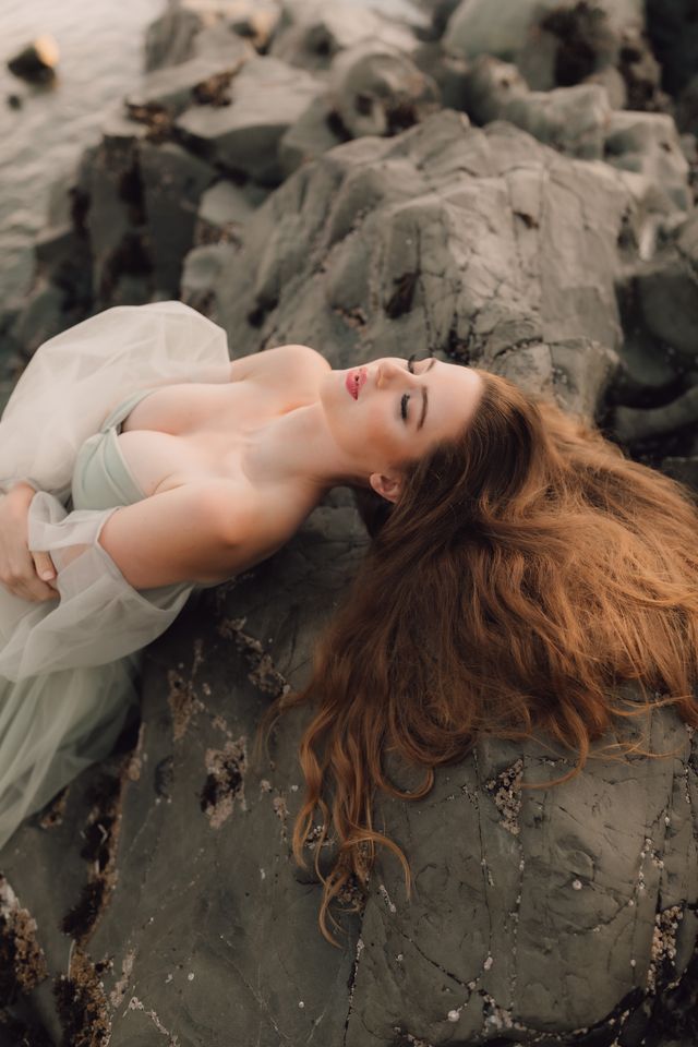 brides hair cascades across a large beach rock