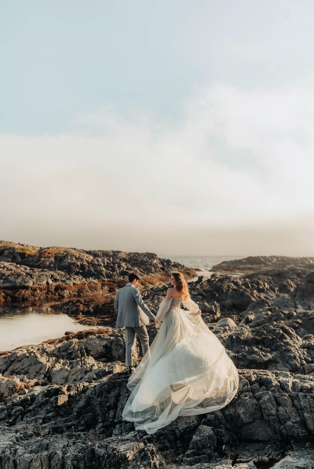 bride in long flowing dress walks on rocks