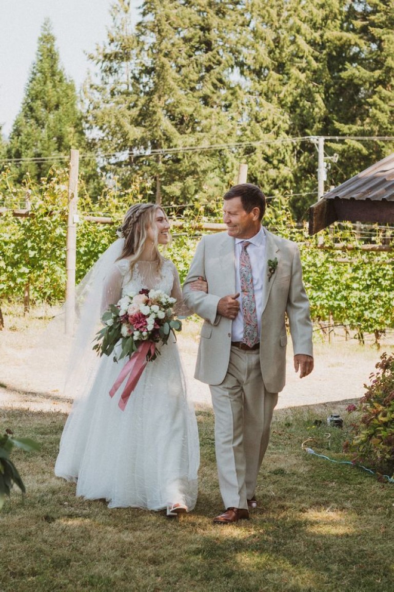 bride's father walks her down the aisle at her outdoor ceremony
