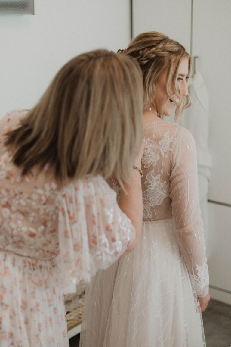bride's mother helps her with back of dress