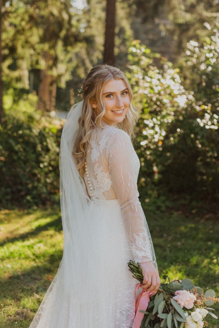 bride smiles looking over her shoulder holding bridal bouquet