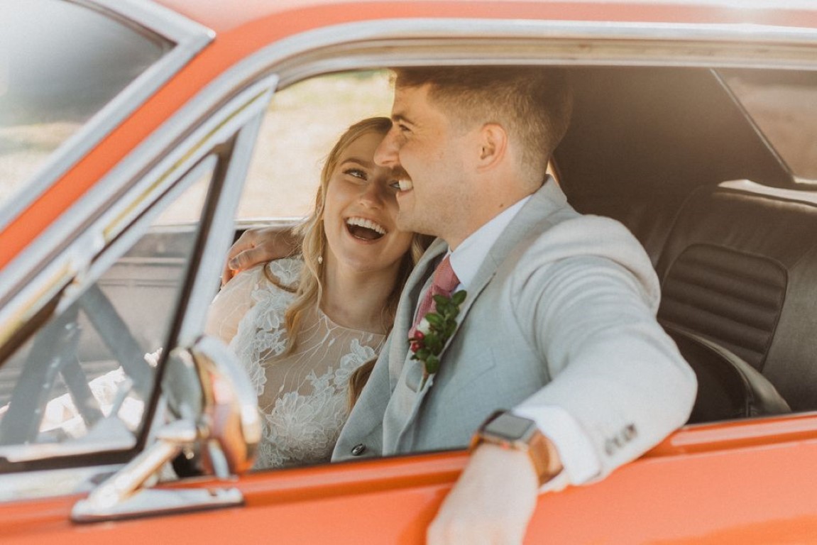 bride and groom cozy up in orange vintage car