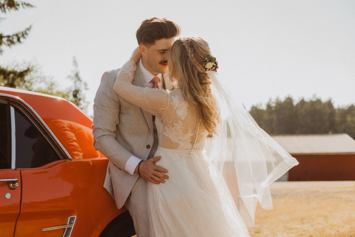 couple leans on orange classic car for shot