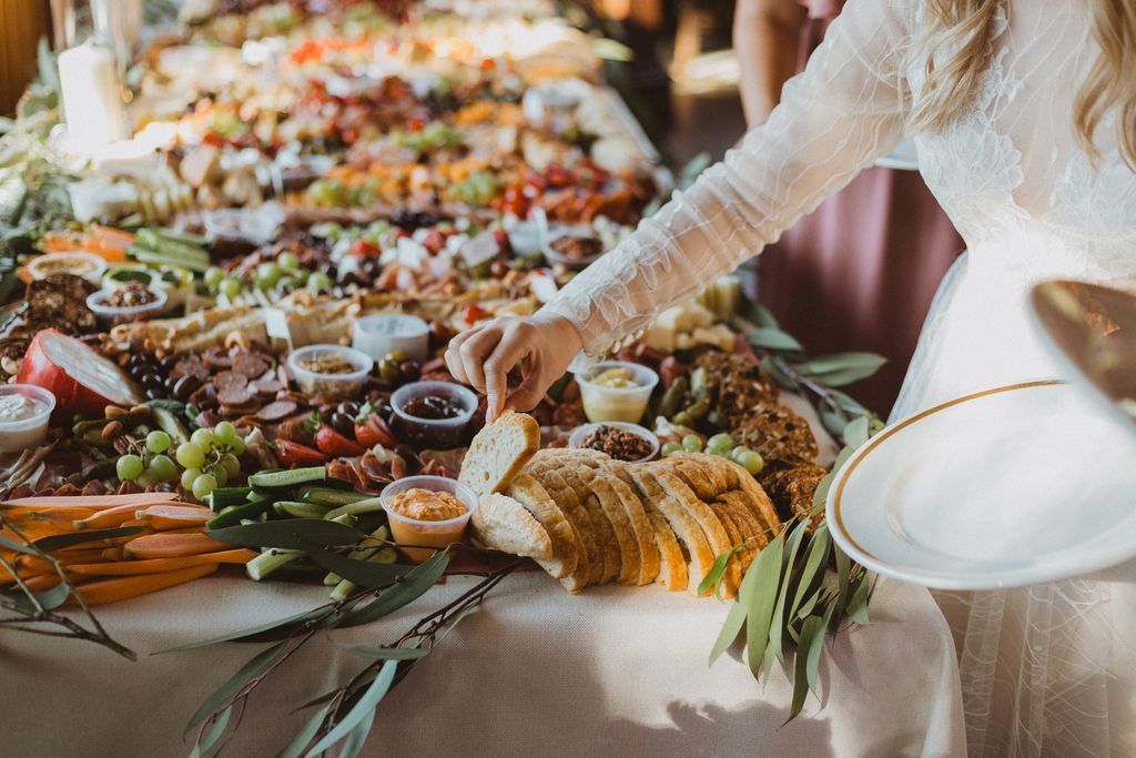 bride takes a piece of bread from impressive charcuterie table