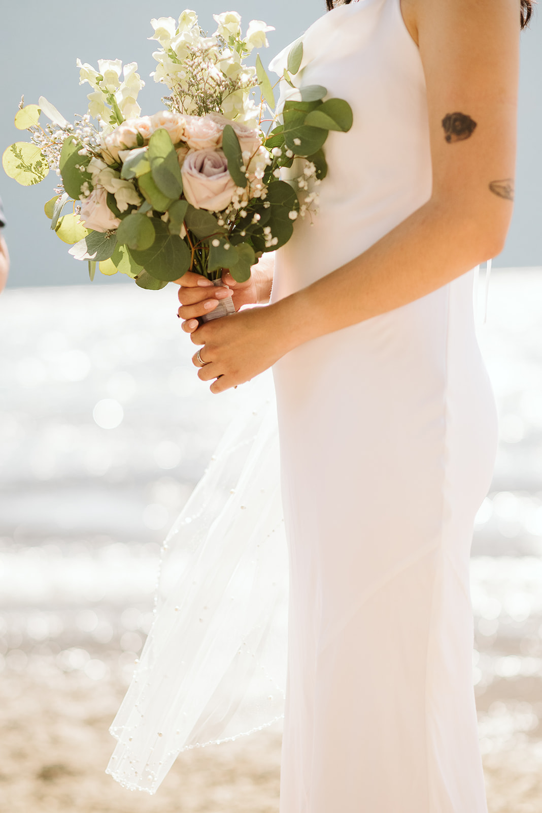 Bride in Park & Fifth gown holding bouquet in front of lake