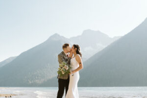 Newlyweds kiss in front of mountain lake in BC