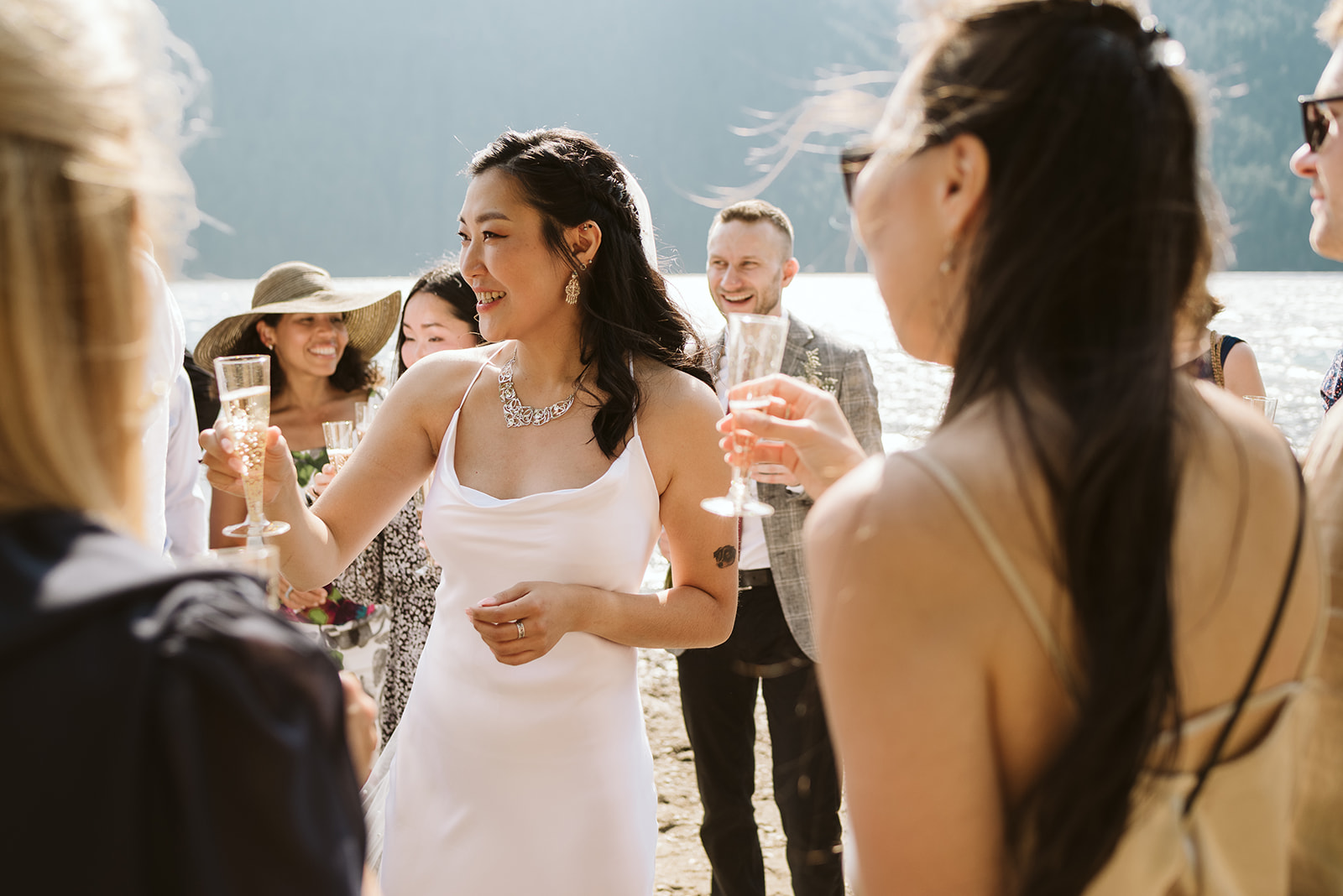 Bride sips champagne after mountain lake wedding ceremony