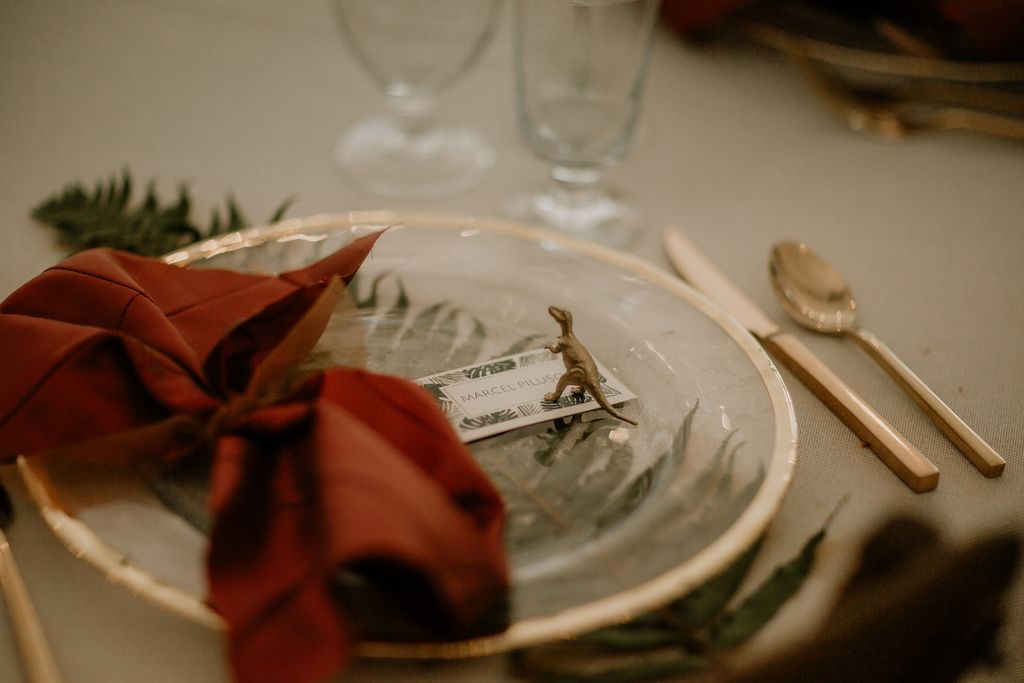 Burnt orange napkin on gold plate with dinosaur skull at Cedar Haven Wedding