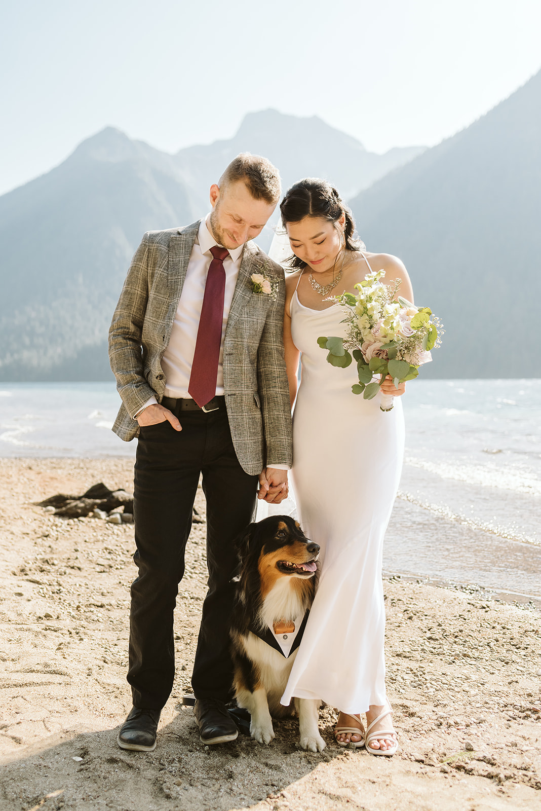 Newlyweds and dog on lake beach