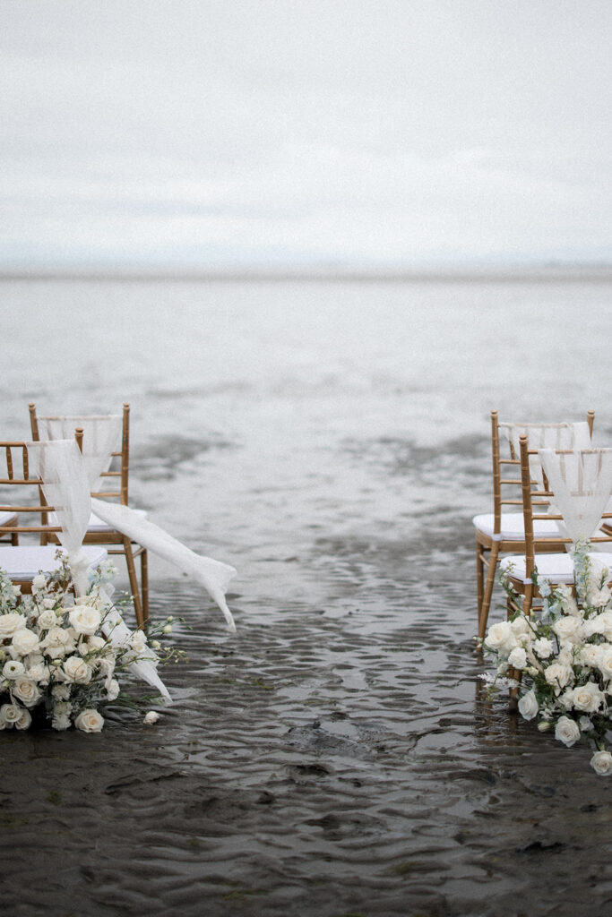 gold Chiavari chairs sit in water on Vancouver beach